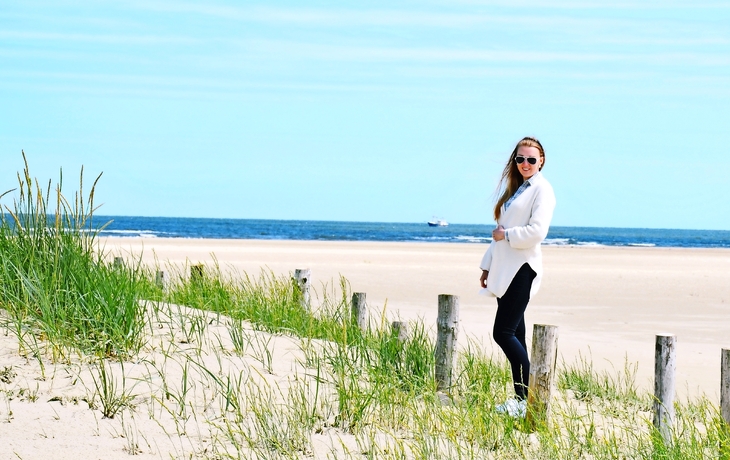 Erholung am Meer - junge Frau steht am Strand